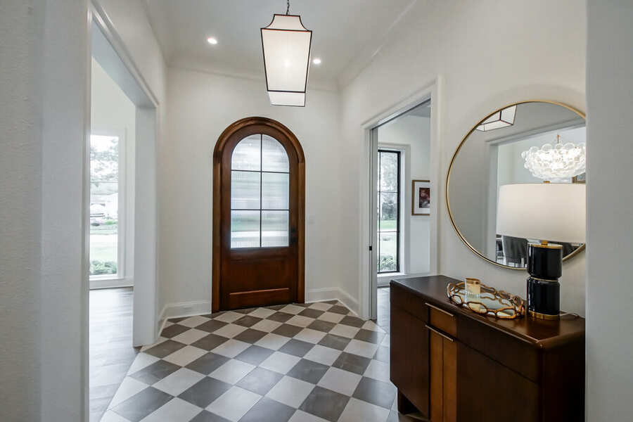 Grand foyer with arched wood front door and checkerboard marble floor