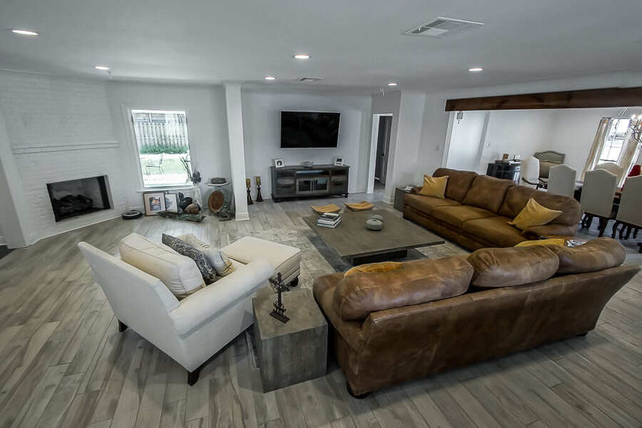 Open living room with painted white-brick fireplace and wood-look plank floors