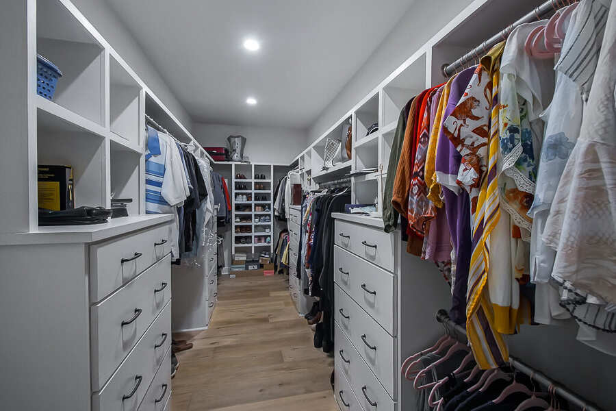 Custom primary walk-in closet with built-in shelving and drawers
