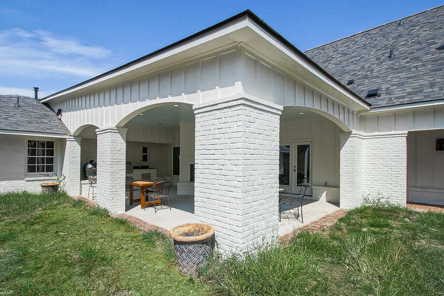 Rear elevation with arched white-brick columns framing the covered outdoor living space