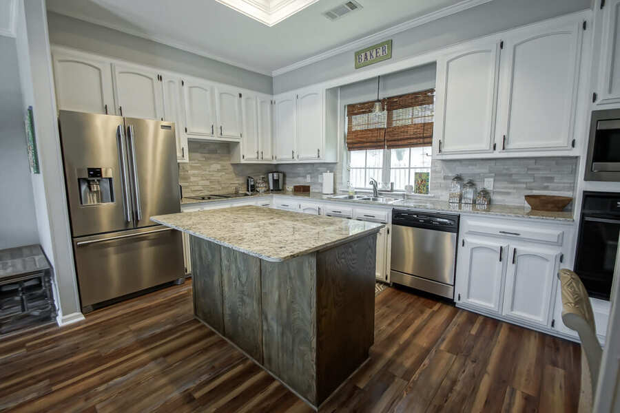 Renovated kitchen with a new center island, granite counters and stainless appliances