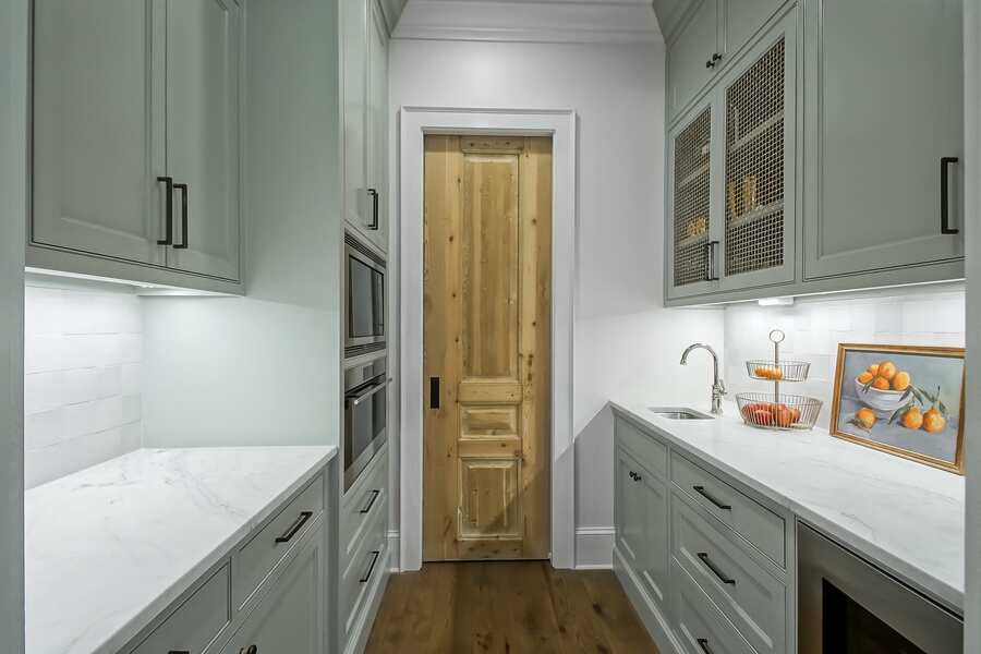 Butler's pantry with sage cabinetry and antique hardware