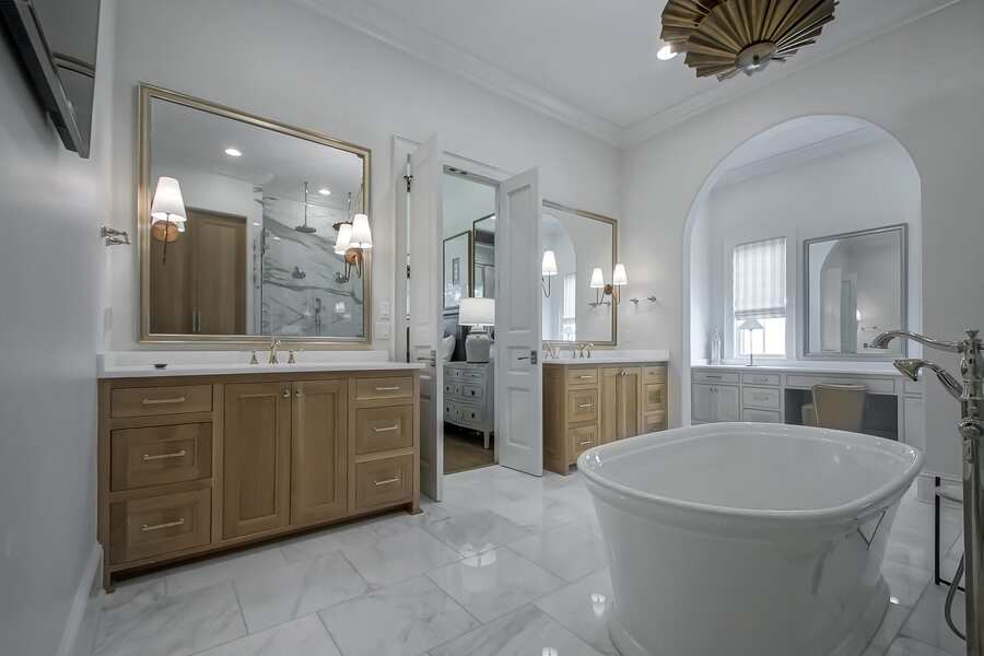 Dual wood vanities in the primary bath with marble flooring