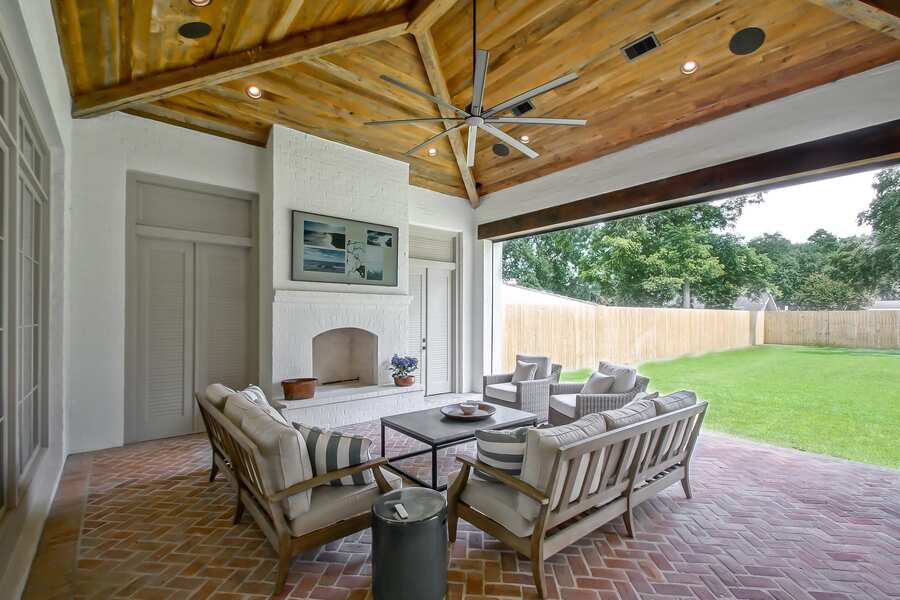 Covered back porch with reclaimed wood vaulted ceiling and brick fireplace
