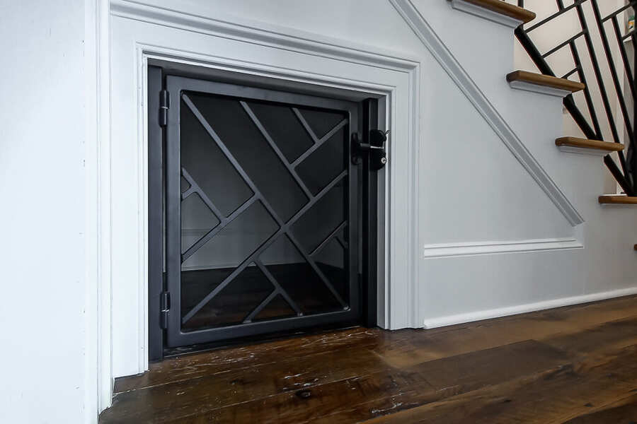 Under-stair storage with a custom black steel lattice door