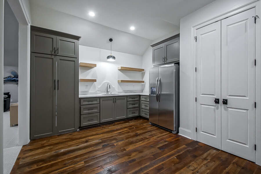 Upstairs wet bar with gray cabinetry, floating oak shelves and a stainless refrigerator