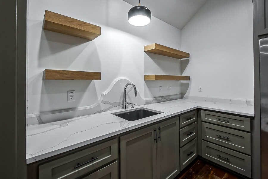 Wet bar detail with marble counter, waterfall backsplash and floating oak shelves