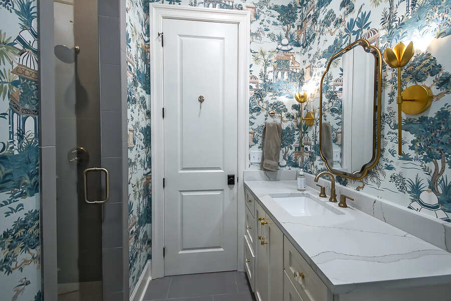 Powder bath with chinoiserie wallpaper, a marble vanity and brass fixtures