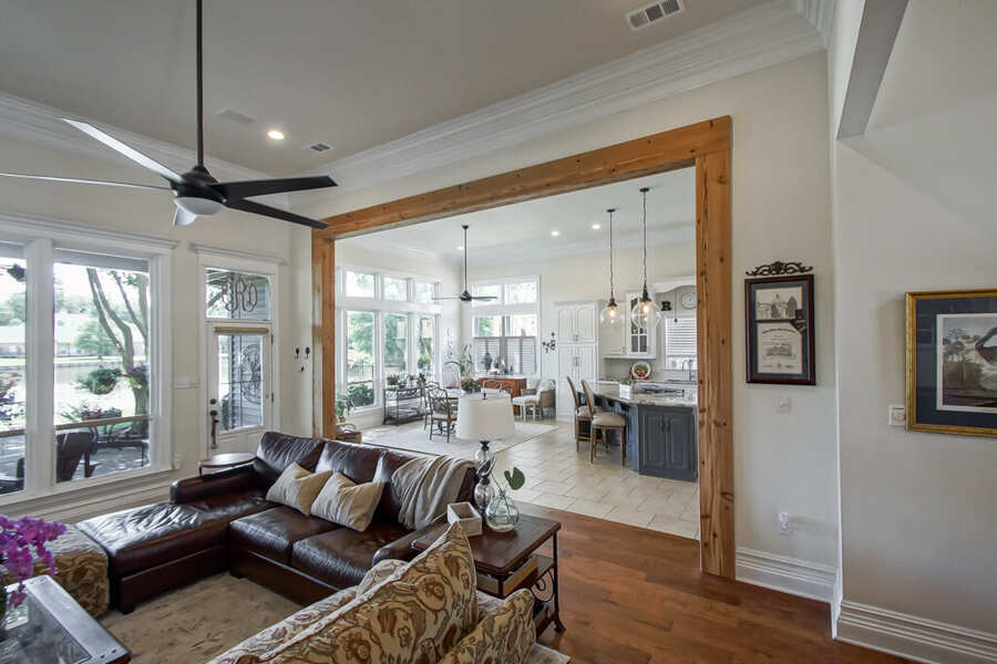 Living room opened to the kitchen beneath a reclaimed-cypress header