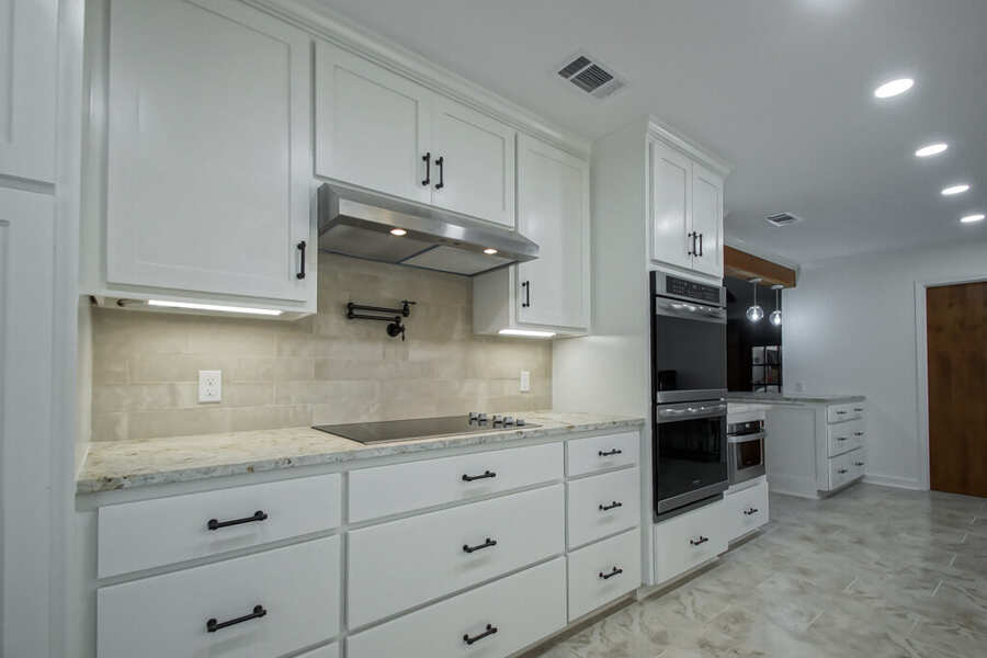 Cooktop wall with stainless hood, pot filler and travertine tile backsplash
