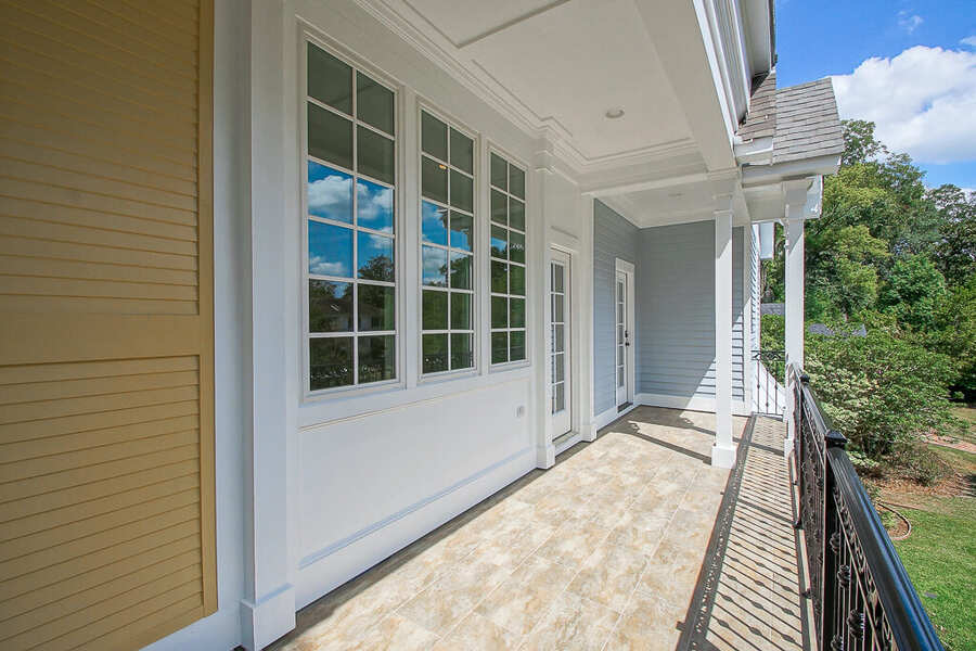 Upper covered balcony with tile flooring and wrought-iron railing