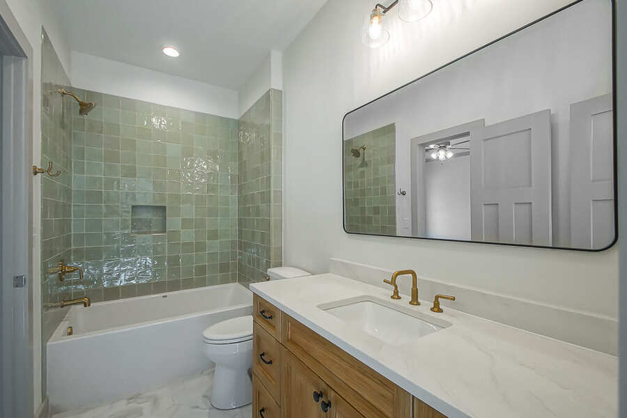 New bath with a green tile tub-shower surround and brass fixtures