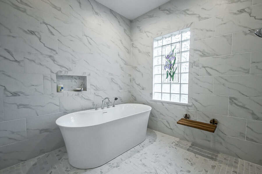 Freestanding soaking tub beside the stained-glass window