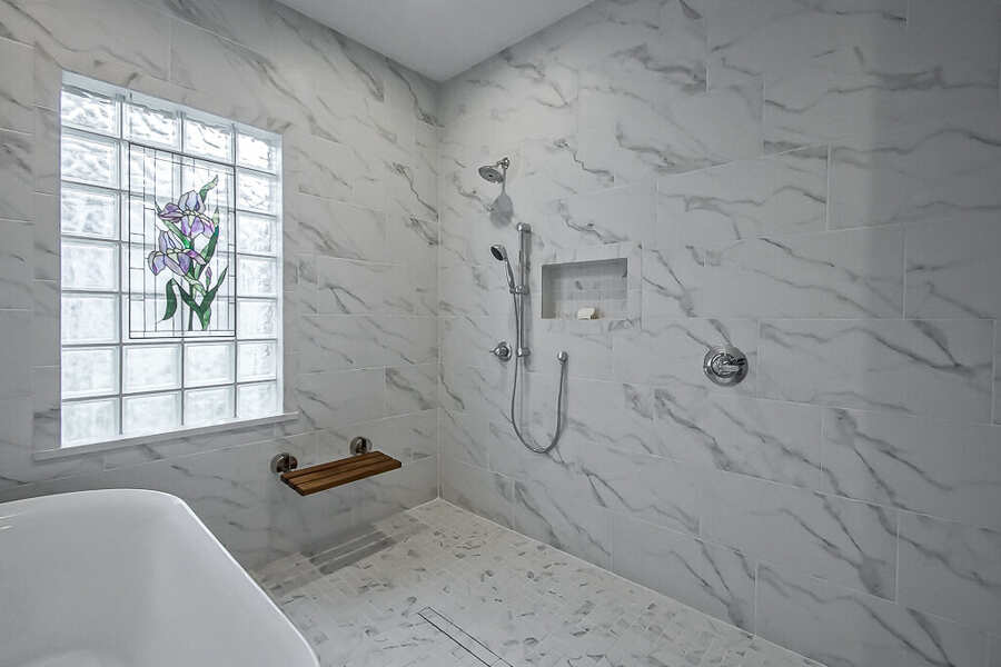 Curbless shower entry with a teak bench and handheld sprayer