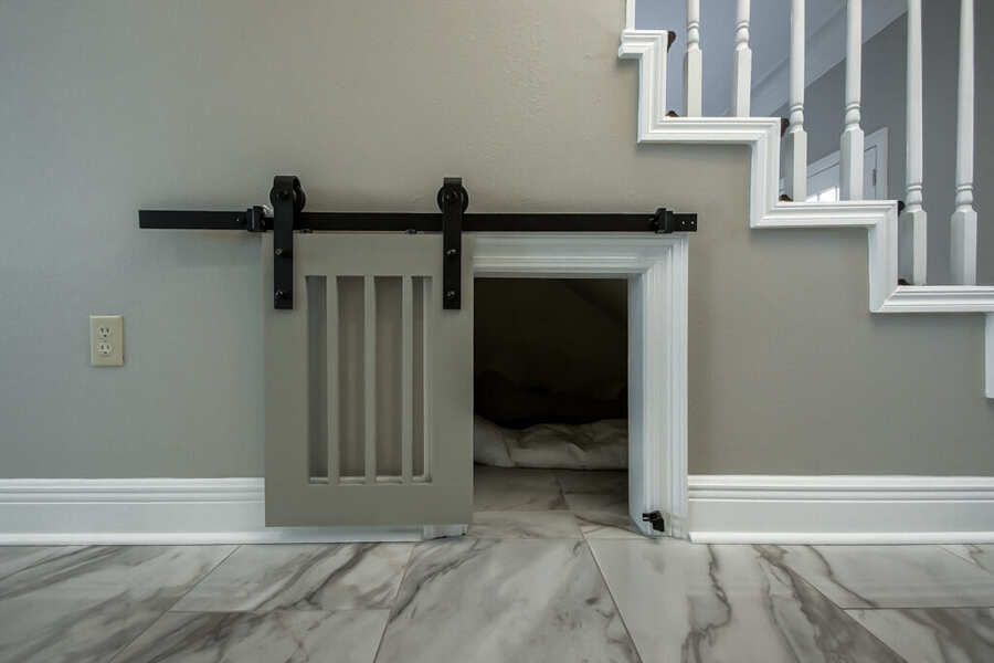 Custom barn-door pet nook built into the under-stair space