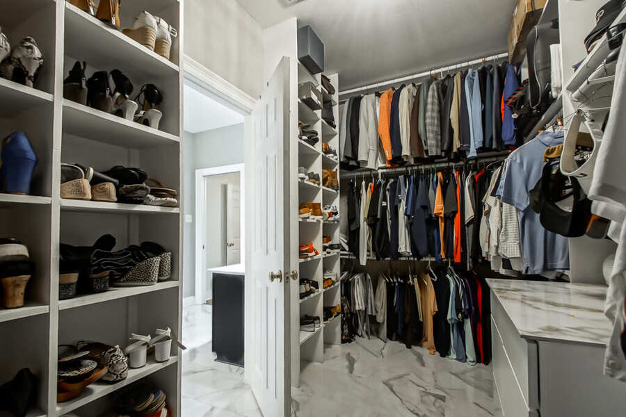 Custom primary closet with built-in shoe shelving and hanging rods