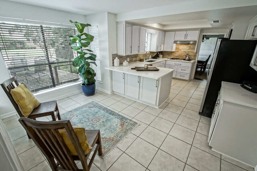 Renovated open-concept kitchen with white shaker cabinetry and a quartz peninsula