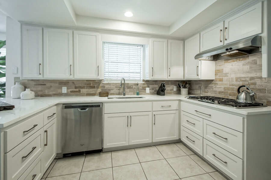 Kitchen sink run with new dishwasher and travertine backsplash