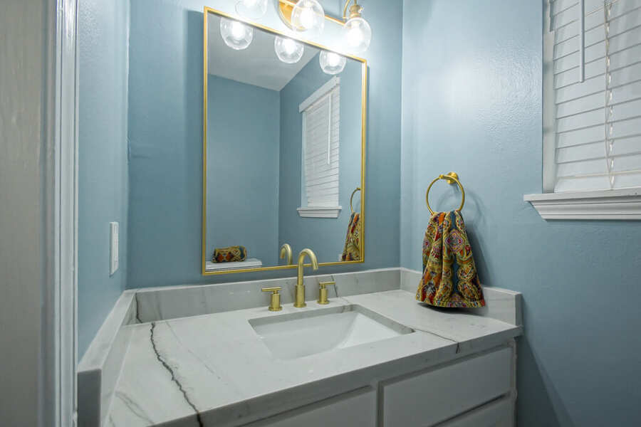Refreshed half bath with a quartz vanity and brass fixtures